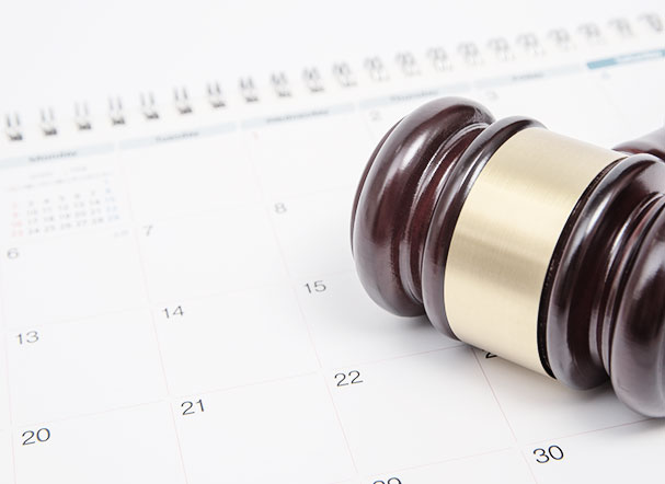 Gavel, brown, used in court sessions, positioned above a calendar