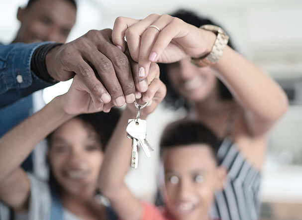 Familia composta por um homem, uma mulher e duas crianças segurando um molho de chaves residenciais