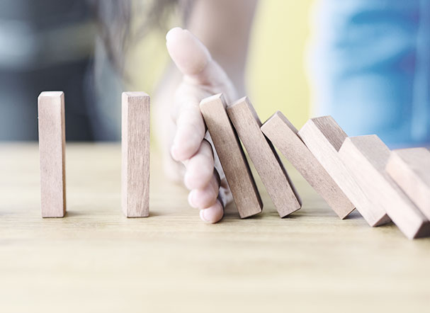 mão segurando blocos de madeira dispostos em sequência, posicionados em cima de mesa